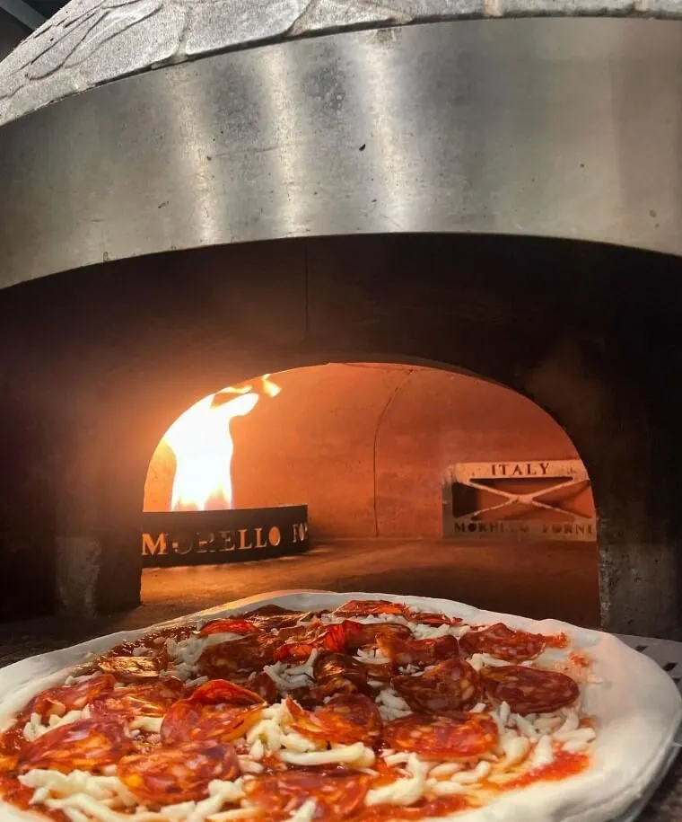 Pepperoni pizza in front of the wood-fired oven